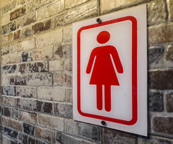 Front view of public restroom or toilet with man and women signs on brick wall. Way to clean restoom man and women toilet sign.